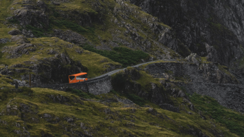 A red coach driving up a steep rural road in England