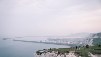 Group of people sitting at the top of the Dover cliffs overlooking the sea on a foggy day