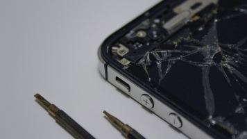 A close-up shot of the corner of a smartphone with a smashed screen