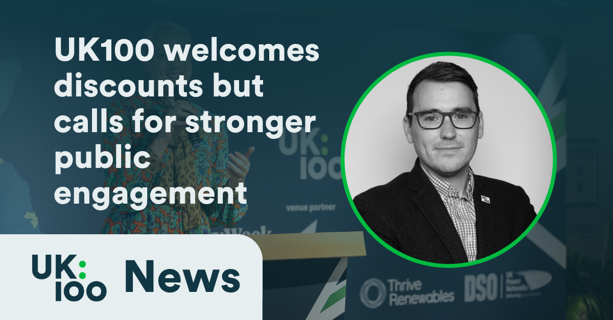 UK100 news graphic featuring a professional headshot of a man in glasses and dark suit jacket against a green circular border. The headline reads 'UK100 welcomes discounts but calls for stronger public engagement' overlaid on a background showing blurred conference or event imagery with the UK100 logo visible.
